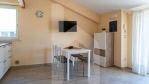 A compact kitchen with a dining table, chairs, a clock, a TV, and a refrigerator. - D'Annunzio Residence - Sedna - Apartment a stone's throw from the sea (Pineto)