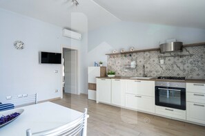 Een moderne keuken met witte kasten, een ingebouwde oven en een decoratieve spatwand.