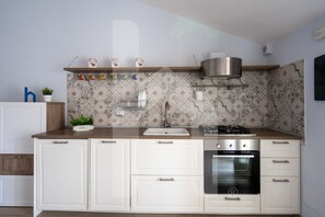 Een moderne keuken met witte kastjes, een roestvrijstalen afzuigkap en een decoratieve spatwand.