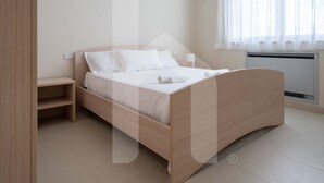 Un dormitorio moderno con una cama de madera, una mesita de noche y una ventana con cortinas translúcidas.