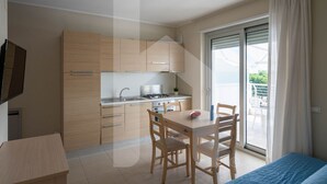 Una cocina moderna con armarios de madera, una mesa de comedor y sillas. Hay un ventanal corredero que da a un espacio exterior.