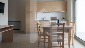 Una cocina moderna con armarios de madera, una mesa de comedor con sillas y un amplio ventanal que proporciona luz natural.