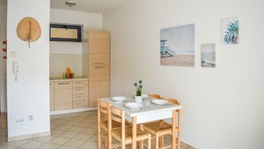 Une cuisine compacte avec des meubles en bois, une table à manger pour quatre personnes et une décoration murale sur le thème de la plage.
