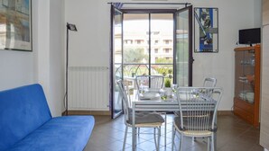 A dining area with a table set for four, a blue sofa, and a view through a glass door to an outdoor balcony. - Micaene D05 - Perseo - First floor apartment with balcony (Pineto)