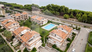 A residential area with apartment buildings, a swimming pool, and a view of the sea.
