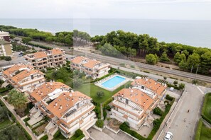 Un complesso residenziale con diversi edifici, una piscina e vista sul mare.