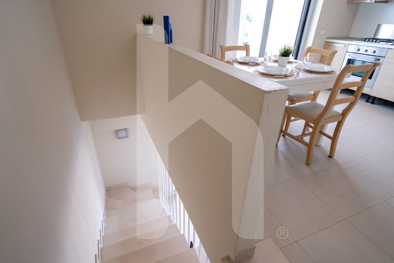 A modern kitchen with a dining area, a staircase, and a view of the outside.