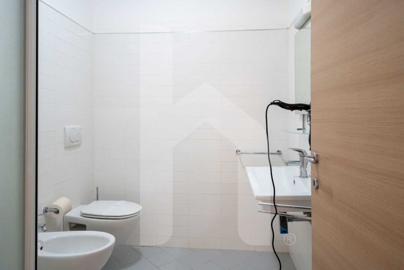 Ein kleines, modernes Badezimmer mit Toilette, Bidet und Waschbecken.