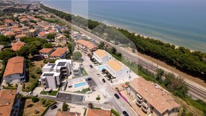 Vista aérea de un pueblo costero con edificios residenciales, una playa y una autopista.