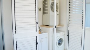 Ett tvättrum med tvättmaskin, torktumlare och ett ventilationssystem.