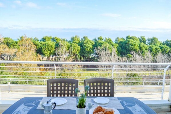 A table set for two with a view of trees and a railing.