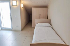 A bedroom with a single bed, a wardrobe, and a door leading to a balcony.