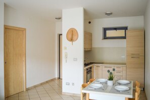 A modern kitchen with wooden cabinets, a built-in stove, and a dining area with a table set for four. - G.Bay C14 - First floor apartment with balcony overlooking the sea and swimming  (Foggetta)