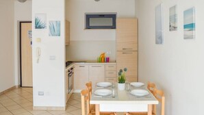 A compact kitchen with a microwave, wooden cabinets, and a dining area with a table set for two. - G.Bay C21 - Second floor apartment with balcony overlooking the sea and the pool (Foggetta)
