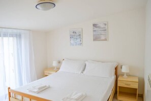 A bedroom with a bed, two bedside tables, and a window with curtains.