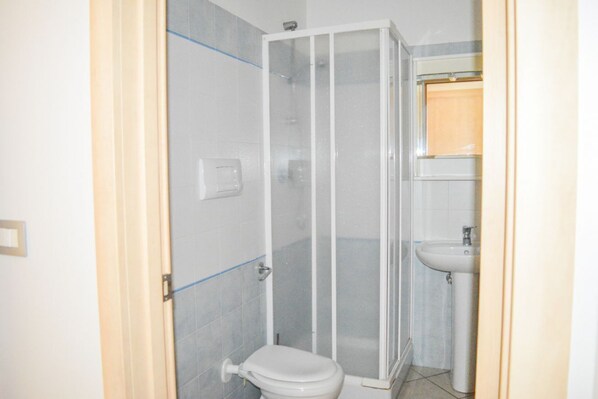 A bathroom with a glass-enclosed shower, a toilet, and a sink.
