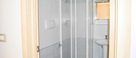 A bathroom with a glass shower enclosure, a toilet, and a sink.