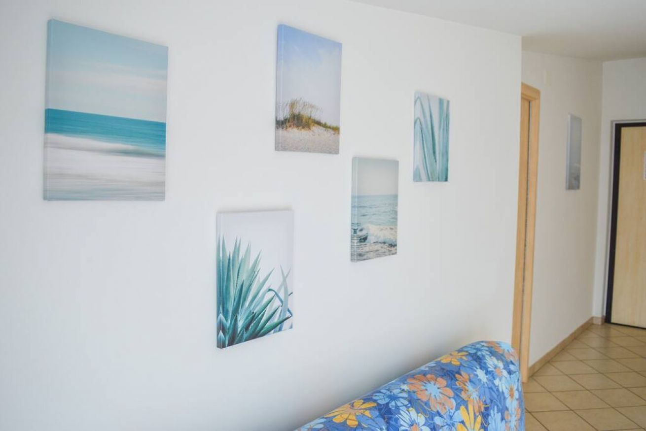 A hallway with a floral sofa, a wooden door, and four framed artworks on the wall.