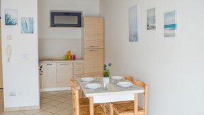 A modern kitchen with a dining area, featuring a wooden cabinet, a microwave, and a table set for four. - G.Bay C25 - Second floor apartment with balcony and hill view (Foggetta)
