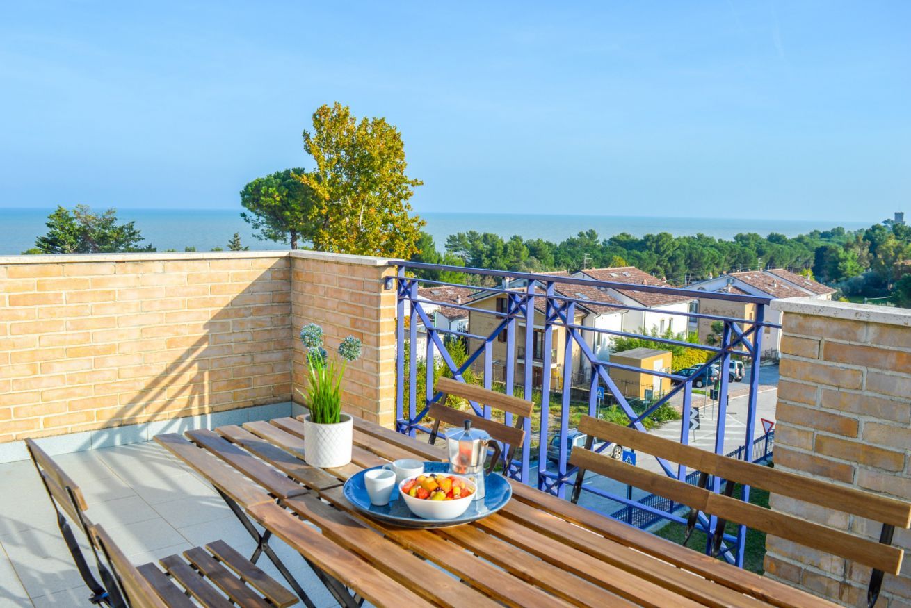 En balkon med et bord dækket til morgenmad, med udsigt over kysten.