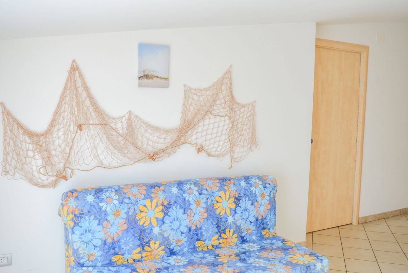 Une pièce avec un canapé bleu à motifs floraux, une porte en bois et un filet décoratif accroché au mur.