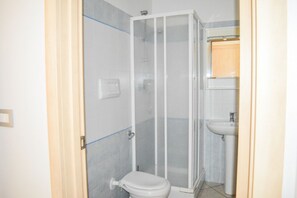 Une salle de bain avec une douche à parois de verre, des toilettes et un lavabo.