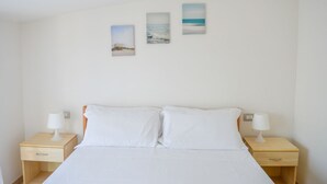 Une chambre d’hôtel comprenant un lit, deux tables de chevet et trois tableaux accrochés au mur.