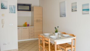 Une cuisine compacte équipée d’un four à micro-ondes, de meubles en bois et d’un coin repas avec une table dressée pour quatre personnes.