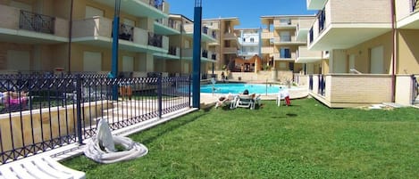 A courtyard with a swimming pool, multiple balconies, and outdoor seating areas.