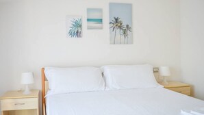 Ein Schlafzimmer mit einem Bett, zwei Nachttischen und drei an der Wand befestigten Bildern.