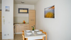 Una cocina compacta con armarios de madera, microondas integrado y un pequeño comedor con una mesa para dos.