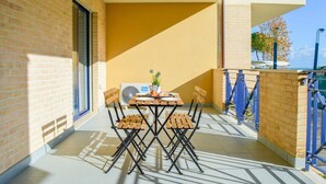 A balcony with a table and chairs, a potted plant, and a view of the sea. - G.Bay D08 - Ground floor apartment with balcony and pool view (Foggetta)
