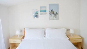 Ein Schlafzimmer mit einem Bett, zwei Nachttischen und drei an der Wand befestigten Bildern.