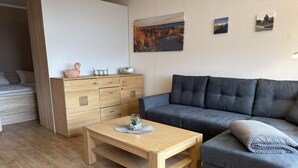 A modern living room with a wooden floor, a grey sofa, a wooden coffee table, a wooden dresser, and a painting on the wall. - Berolina 331 - Sunset - Fantastic sunsets included! (Dahme)