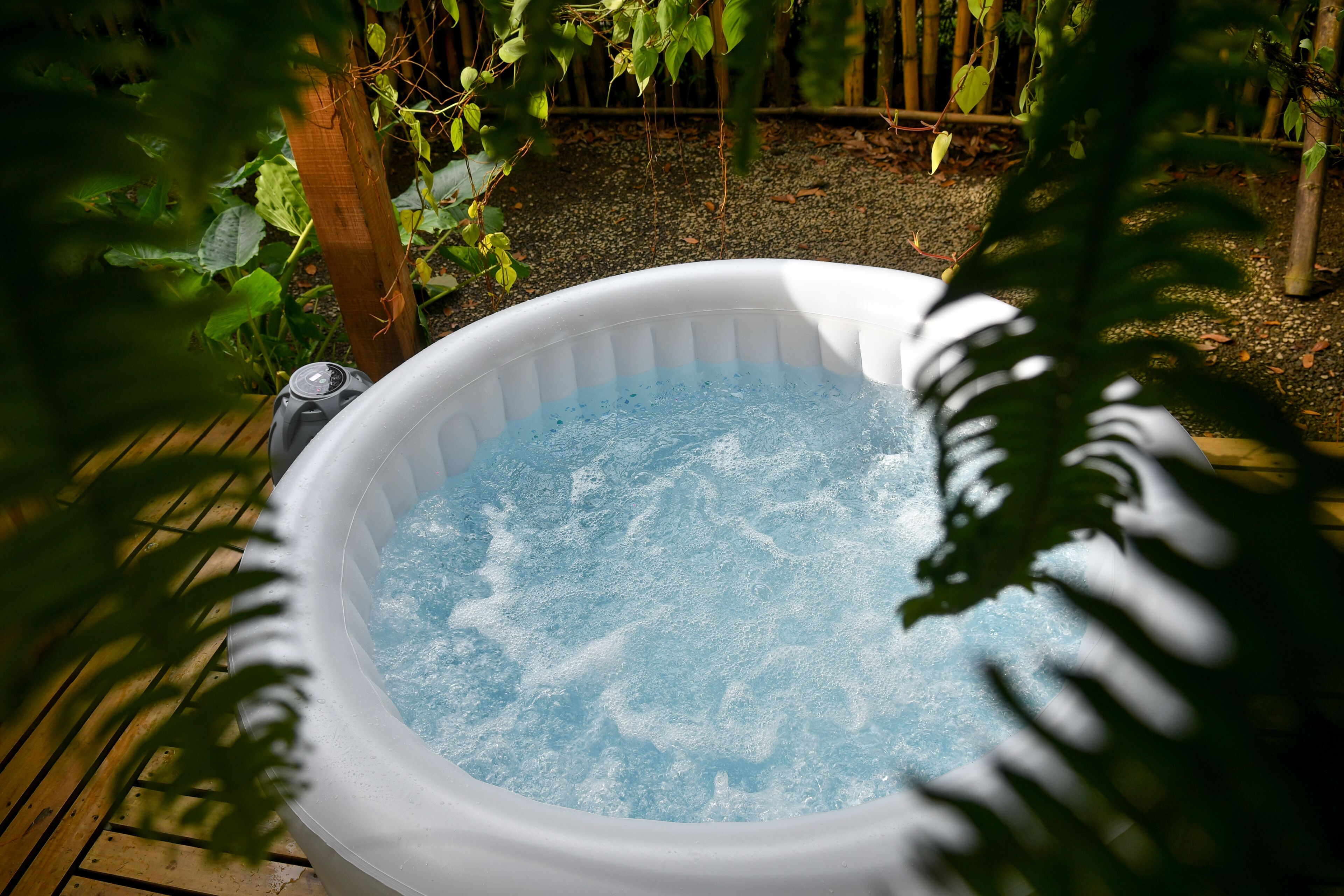 Un bain à remous dans un jardin agrémenté d’une terrasse en bois et de verdure.