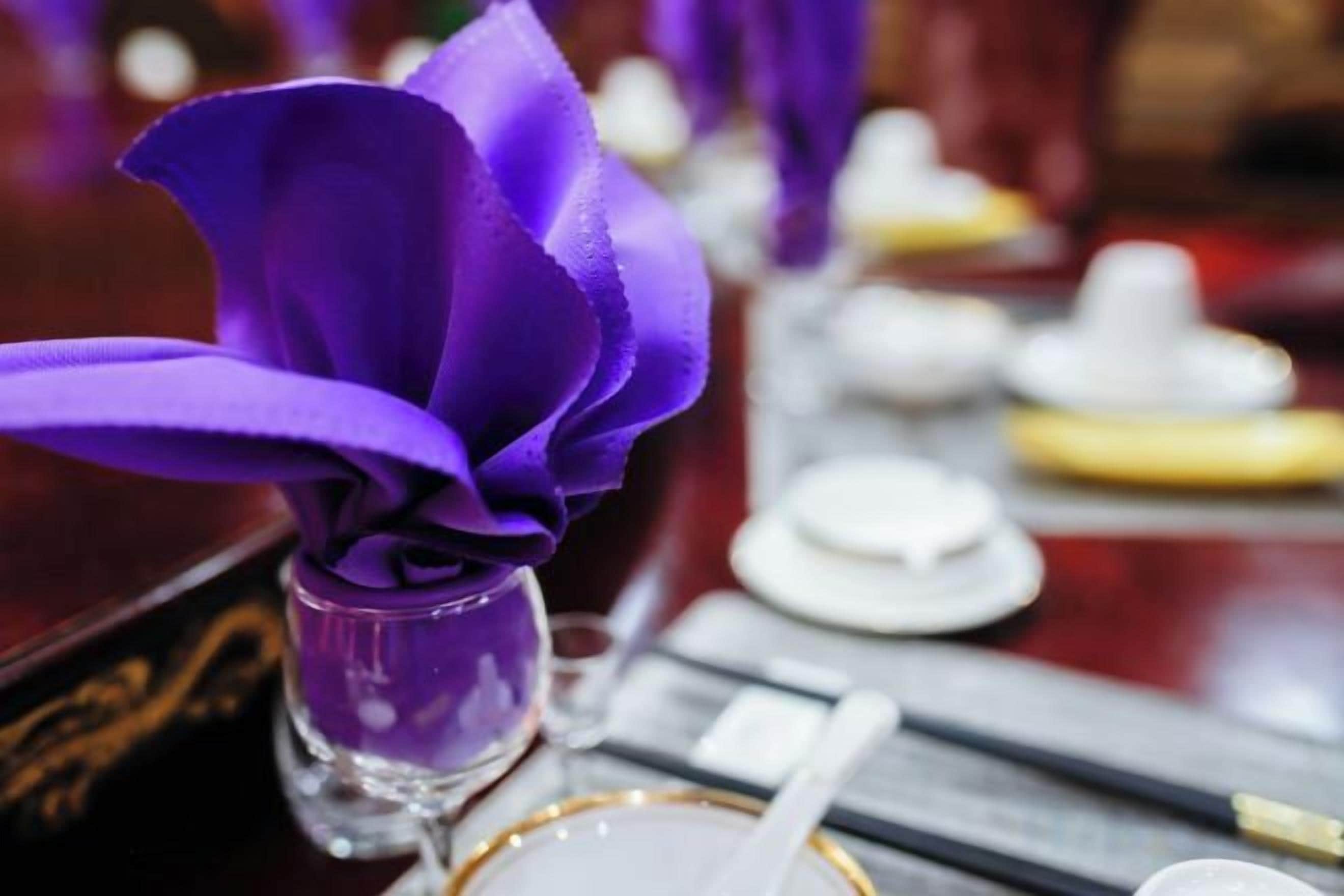 A table setting with a purple flower arrangement, white plates, and chopsticks.