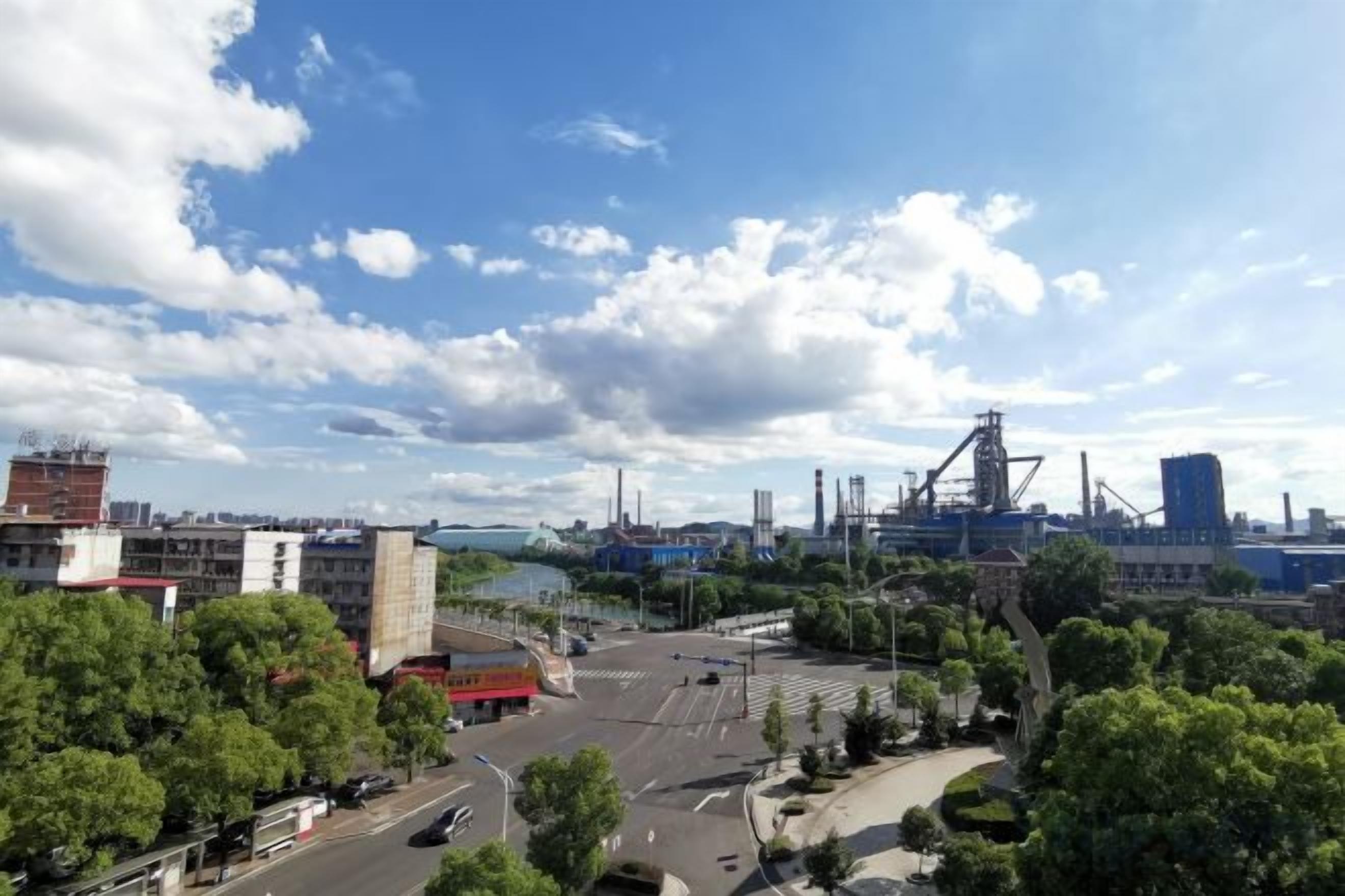 A cityscape with industrial buildings, a river, and a clear sky.