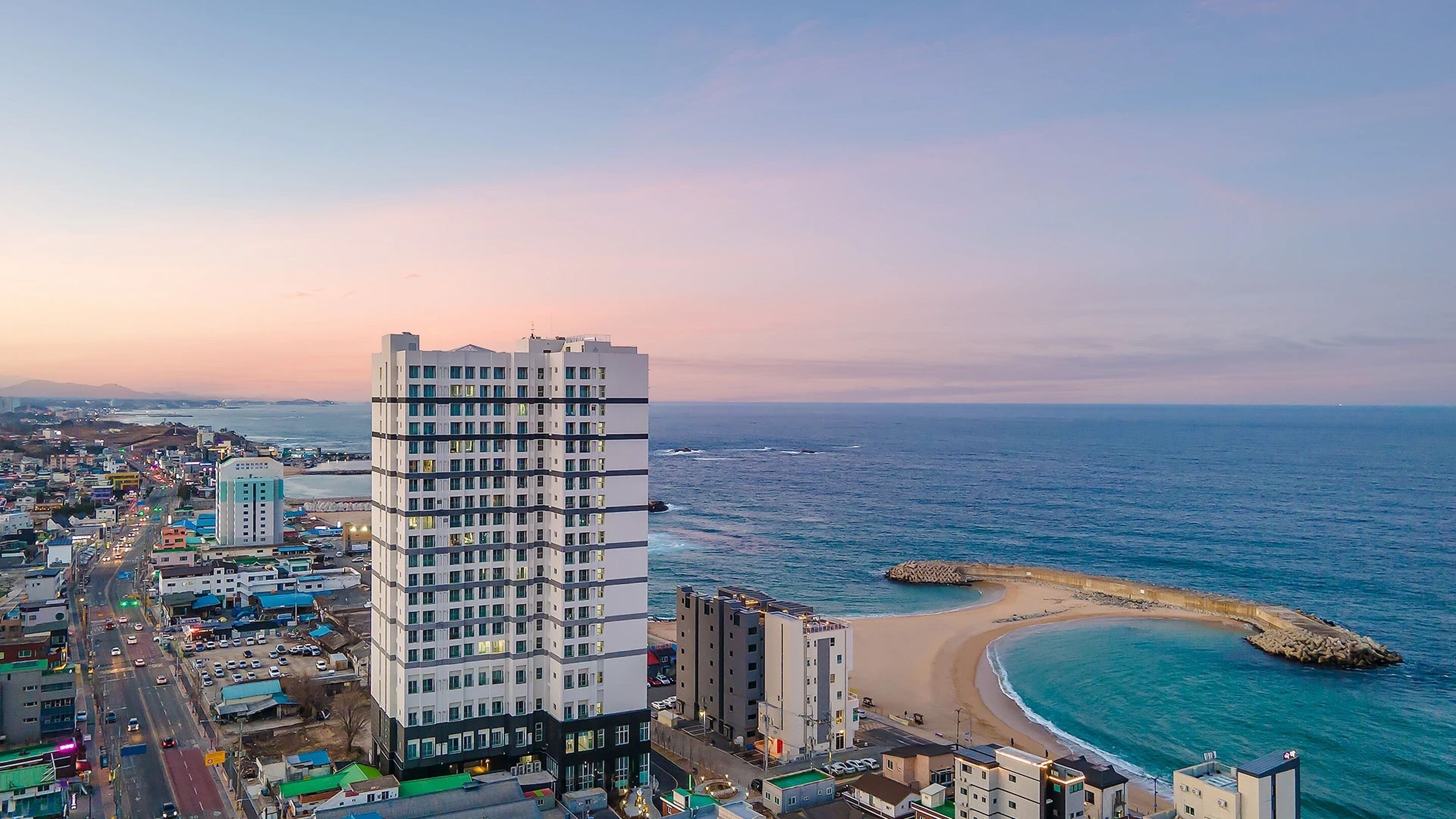 A high-rise hotel with multiple floors, a beachside location, and a view of the ocean.