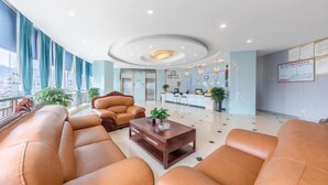 A modern hotel lobby with leather sofas, a reception desk, and a view of the city. - Ruiya Holiday Hotel (Dianjiang County)