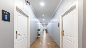 A hotel hallway with white doors, a sign on the left wall, and a tiled floor. - Ruiya Holiday Hotel (Dianjiang County)