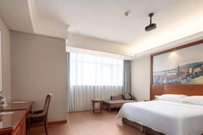 A hotel room with a bed, a desk with a chair, a small table, and a window with curtains. - Vienna Hotel (Taizhou Luqiao Passenger Center) (Taizhou)