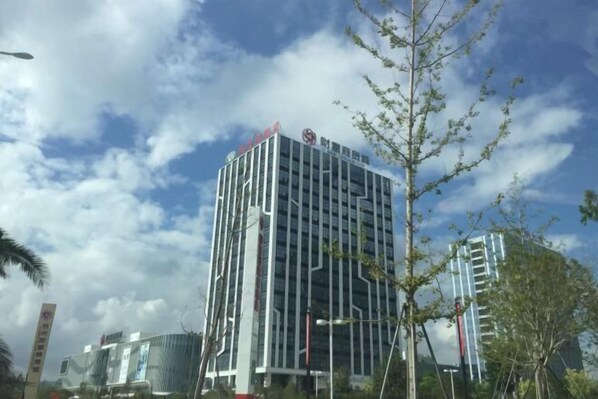 A modern building with a glass facade and a sign indicating it is a hotel. - Vienna Hotel (Taizhou Luqiao Passenger Center) (Taizhou)