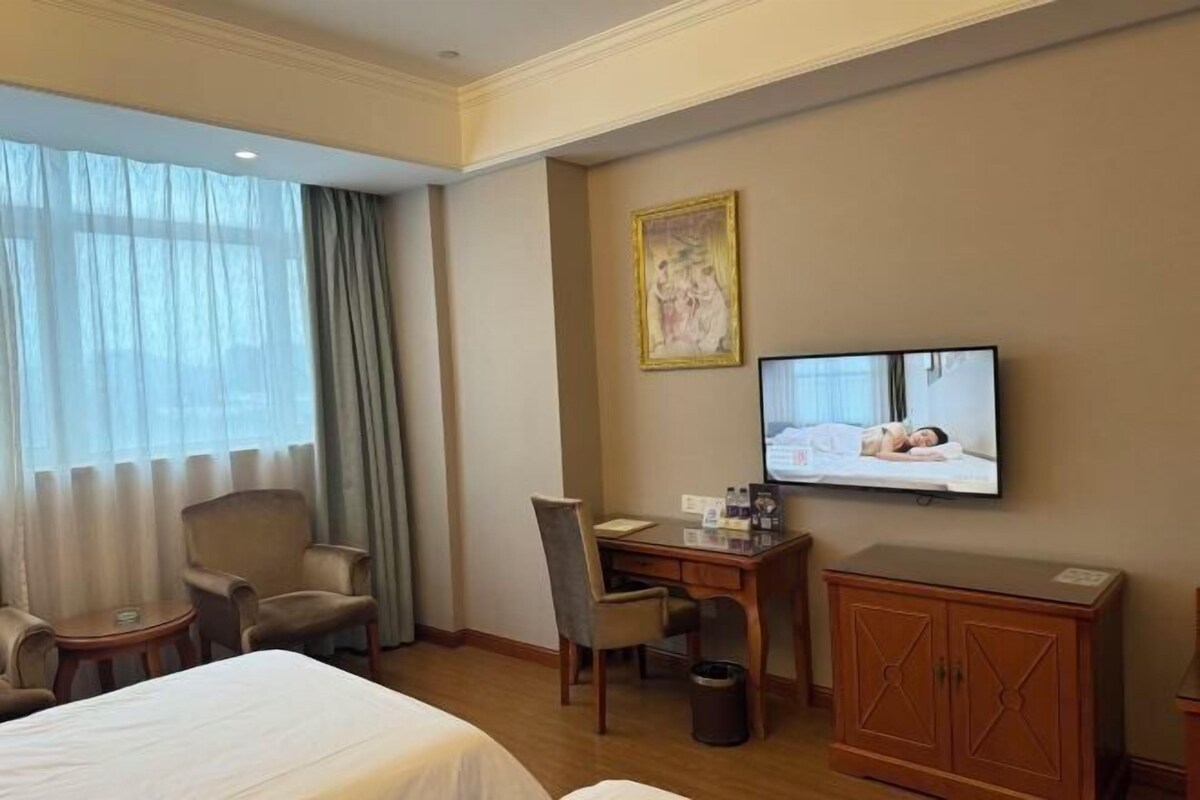 Una habitación de hotel con una cama, un escritorio, una silla, un televisor y un armario.