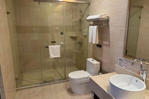 Ein modernes Badezimmer mit einer Duschkabine, einer weißen Toilette und einem Waschbecken mit Spiegel.