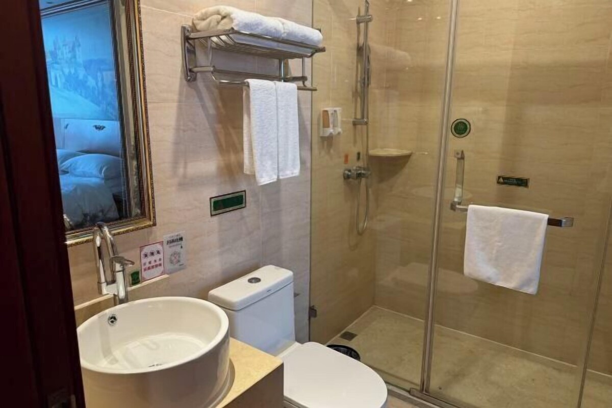 Un baño moderno con ducha acristalada, un lavabo blanco y un inodoro.