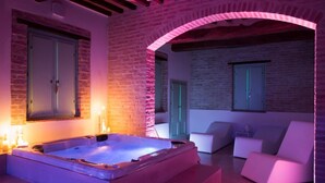 Un espace de détente avec un jacuzzi, des chaises blanches et un mur en briques.