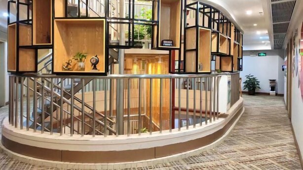 Un espacio circular para leer con estanterías, una escalera y una barandilla.