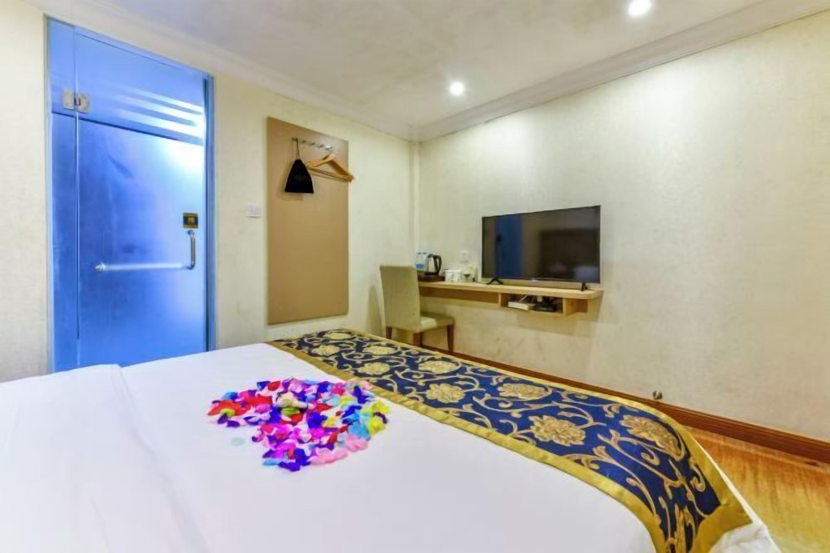 Hotellihuone, jossa on sänky, televisio, työpöytä ja vaatekaappi.