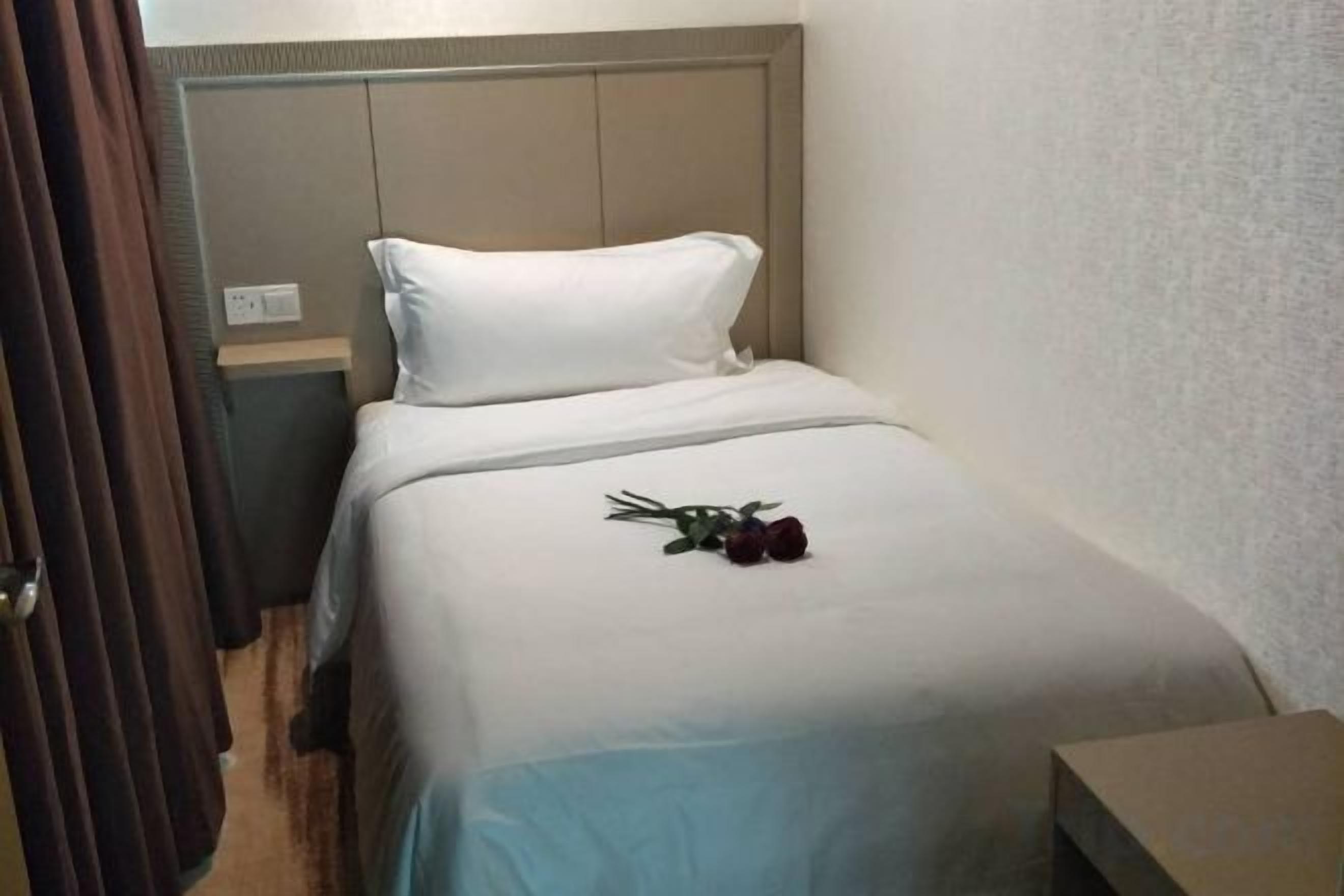 A single bed with a white headboard and a blue bedspread.