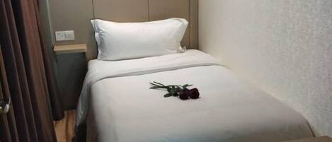 A single bed with a white headboard and a blue bedspread.